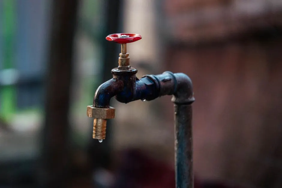 Red-handled shutoff valve on a black water pipe