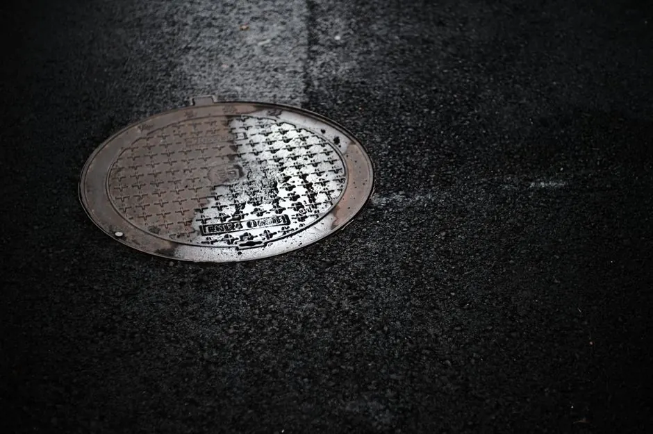 Wet manhole cover on a rainy city street