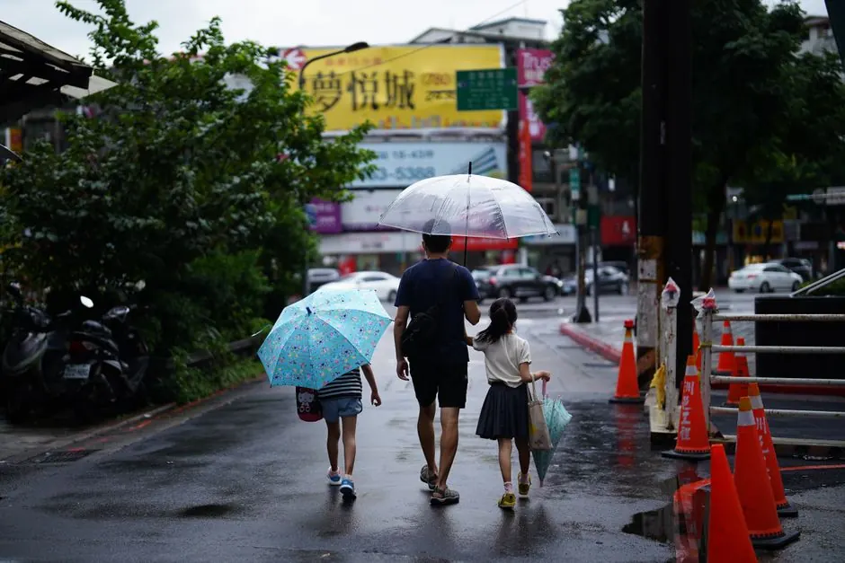 Family with umbrellas walking along a rainy street