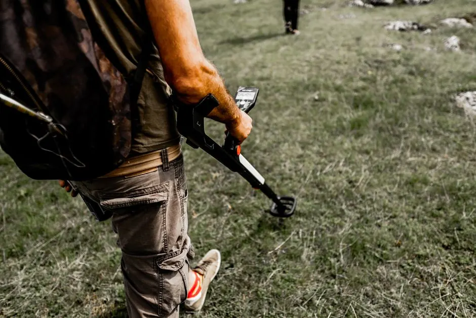 Person sweeping a grassy area with a handheld pipe locator